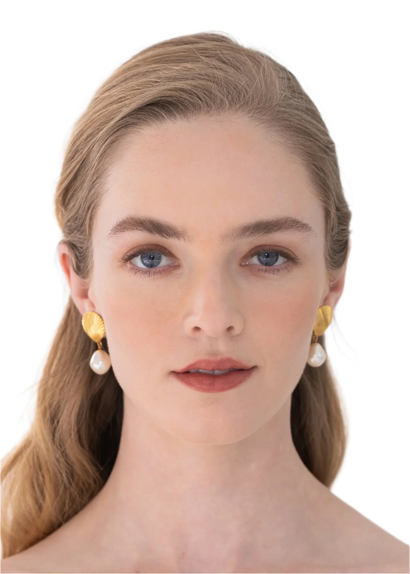 A woman with fair skin and light brown hair wears Jennifer Behr Alana Earrings, showcasing golden scallop shells and baroque pearls against a white background.