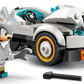 A gray LEGO minifigure with spiky hair holds a wrench beside the white Legos - Toyhouse LEGO® Sonic the Hedgehog™ Silver's Car, featuring gold and black wheels and orange headlights; a black tool is on the ground.