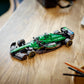 A LEGO® Speed Champions Aston Martin Aramco F1® AMR24 Race Car by Legos - Toyhouse in green and black sits on a wooden table beside pens and a notebook, ideal for Formula 1 fans in 2024.