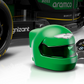 A green racing helmet and small black controller are in front of the rear wheel of a LEGO® Speed Champions Aston Martin Aramco F1® AMR24 Race Car by Legos - Toyhouse, with a bold black and green design.