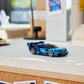 A blue LEGO® Speed Champions Bugatti Vision GT Hyper Sports Car by Legos - Toyhouse sits on a white desk, surrounded by books, photos, and office supplies in the background.