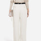 Person facing away from the camera, wearing a beige top, CO Tailored Straight Leg Trouser in white, a black belt, and holding a small light pink chain-strap bag.