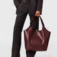 Person in a dark pinstripe suit holding a large burgundy Stella McCartney Logo Reversible Suede Tote.