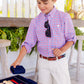 A young boy in a plaid shirt and white Boys' Prepletic™ Charlie's Chinos by The Beaufort Bonnet Company plays backgammon indoors, holding a dice cup above the game board.