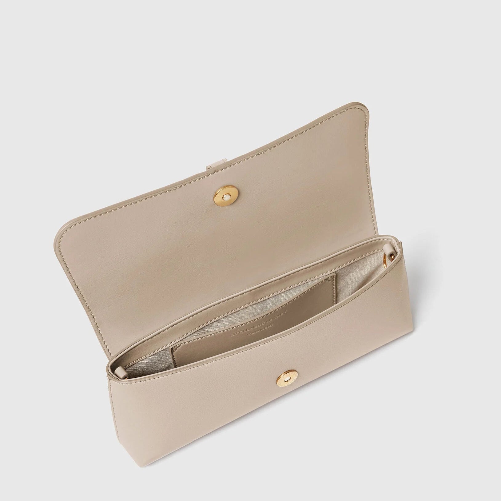A beige wallet with a gold snap closure is open, revealing an empty main compartment and a small interior pocket—an ideal companion to your Stella McCartney Ryder Pouchette Shoulder Bag.