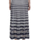 A person wearing the Simkhai Larken Midi Skirt, featuring a bold black and white pattern, paired with black strappy heels, seen from the back.