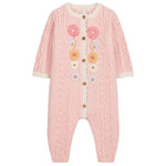 Introducing the Louise Misha Baby Girls’ Drilia Overalls: a pink knitted romper adorned with handmade floral embroidery, cable patterns, and wooden buttons. This charming jumpsuit features delicate white ruffle trim on the chest and cuffs, along with scalloped finishes for an extra-sweet touch.