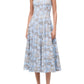 A woman wearing the Staud Wells Dress in Sky Toile, a sleeveless, light blue floral midi dress with a fitted waist and square neckline, paired with brown open-toe heels.