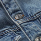 Close-up of The Nipped Collarless Jacket by Frame, featuring blue cotton denim, orange stitching, and metal snap buttons.