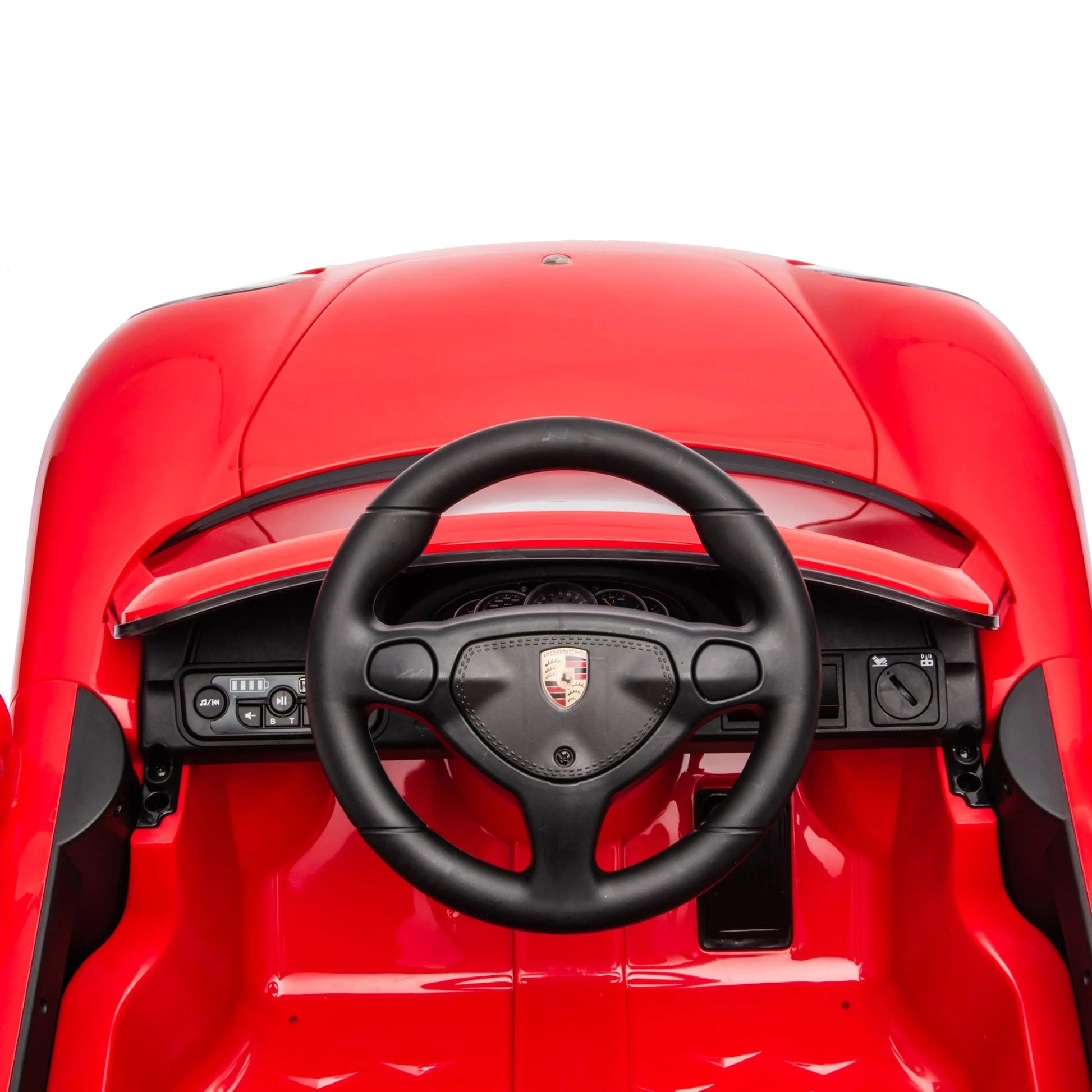 Overhead view of the dashboard and steering wheel of the Freddo 12V Porsche Carrera GT 1 Seater Ride-On, highlighting control buttons and the classic Porsche logo at the center. This motorized vehicle comes with a parental remote control for enhanced safety and convenience.