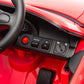 Close-up of the Freddo 12V Porsche Carrera GT 1 Seater Ride-On dashboard featuring a steering wheel, speed control buttons, arrow buttons, a power button, an ignition switch, and a visible foot pedal below in this motorized vehicle.