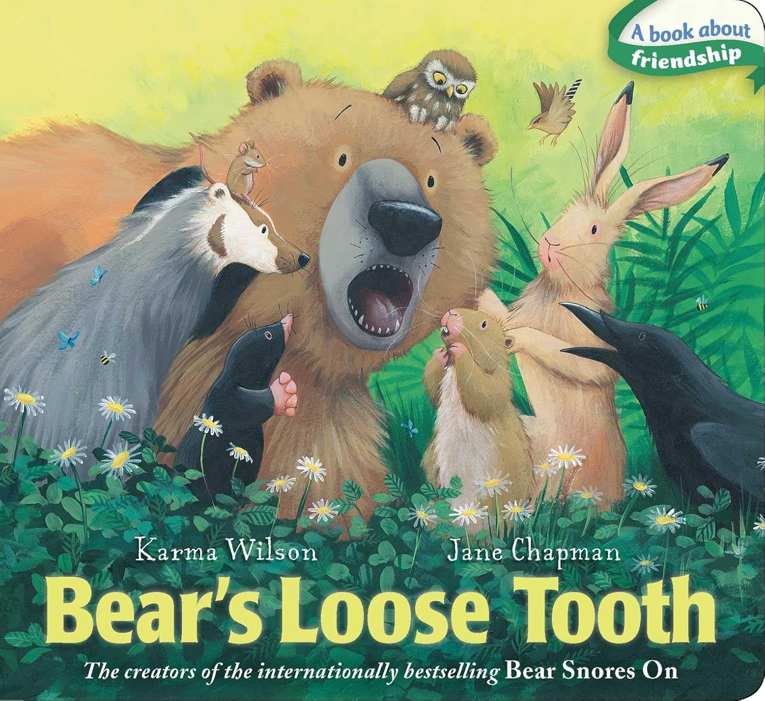 The illustrated cover of Simon & Schuster's "Bear's Loose Tooth" shows Bear with mouth open, losing a baby tooth, surrounded by animal friends in a grassy field. A sticker states: "A book about friendship.