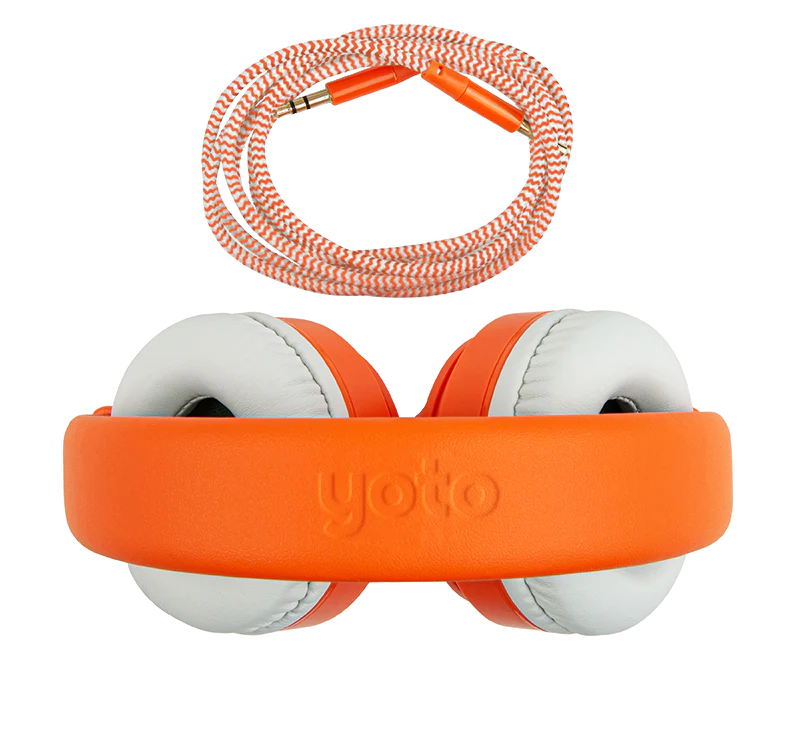 Introducing the Yoto, Headphones Orange by Yoto: orange and white over-ear headphones with the word "yoto" on the adjustable headband. An orange braided audio cable with gold connectors is shown above the headphones. The lightweight, durable construction includes kid-safe volume limiting for safe listening.
