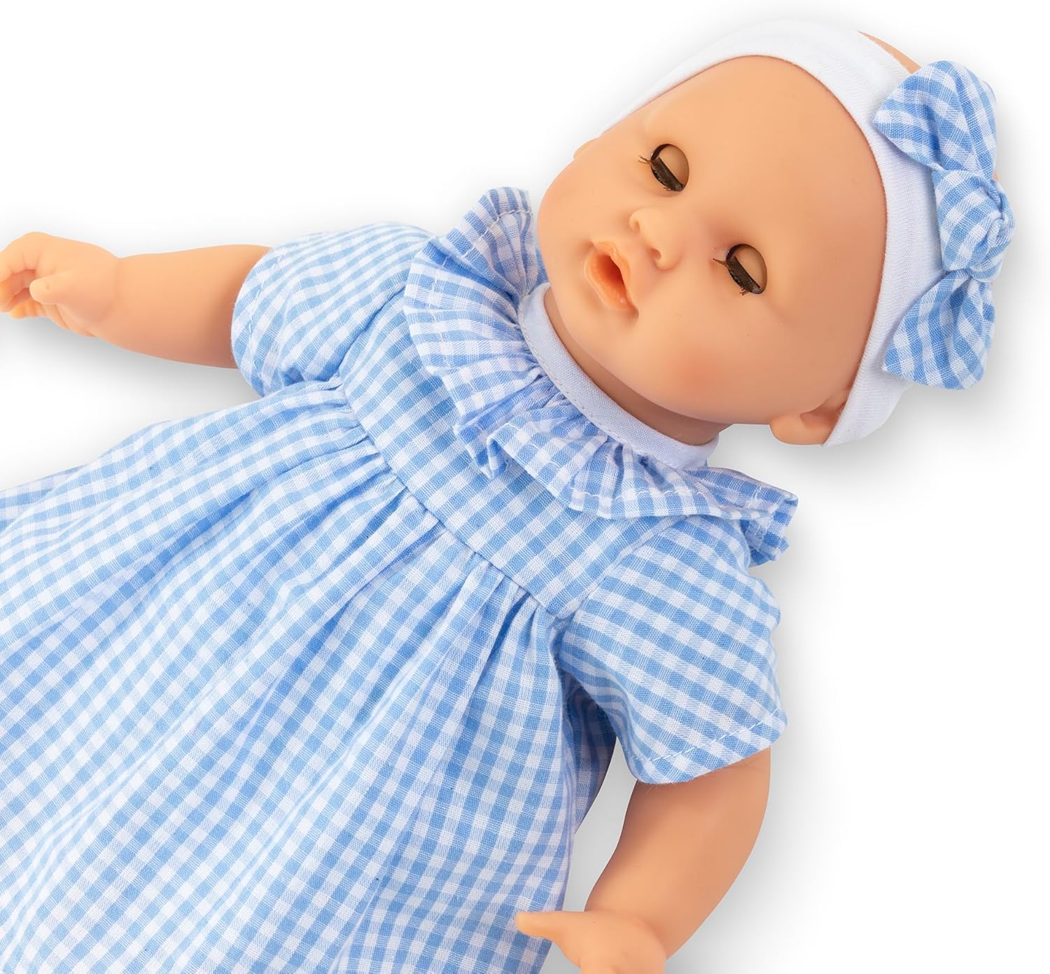 The Premier Calin - Milly Doll by Corolle is a soft-bodied baby doll dressed in a blue and white gingham dress with a matching headband, shown lying on a white background.