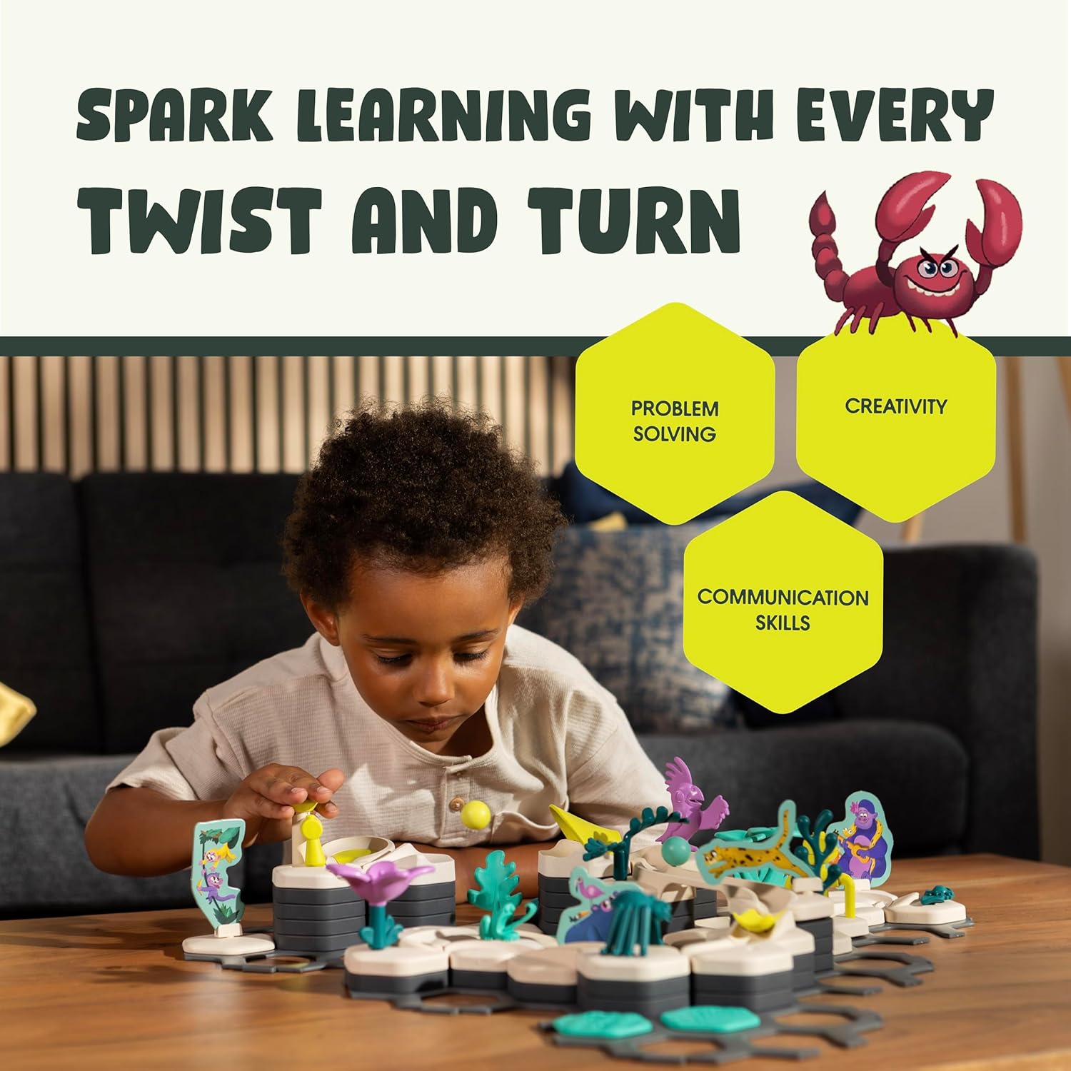 A young child plays with the GraviTrax Junior: Desert Starter Set by GraviTrax on a living room table, surrounded by illustrated icons highlighting problem solving, creativity, and communication skills.