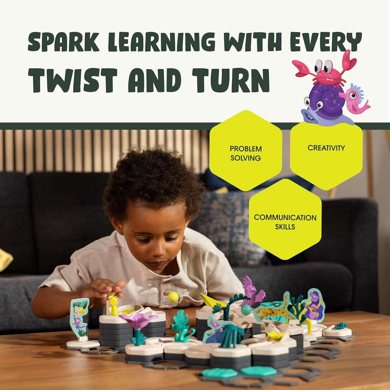 A young child sits at a table playing with the GraviTrax Junior: Ocean Starter Set by GraviTrax, surrounded by colorful pieces that inspire problem solving, creativity, and communication skills in this engaging STEM toy.
