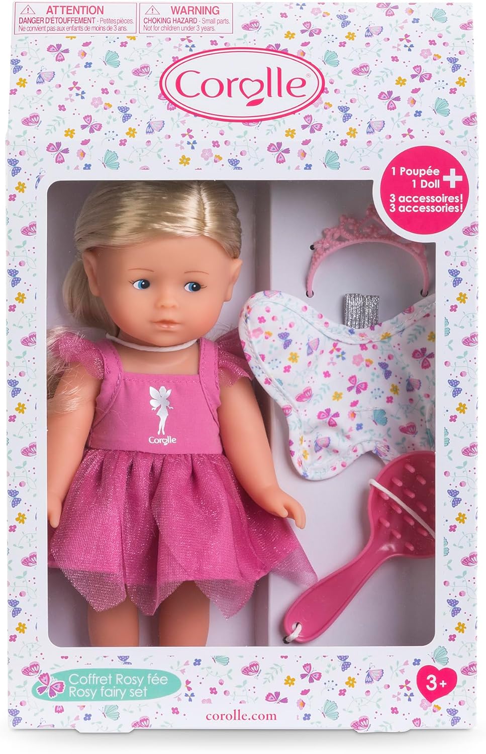 The Corolle Rosy Fairy Set features a doll in a pink dress with butterfly wings, a headband, and a pink hairbrush, all presented in a floral gift box for ages 3 and up.