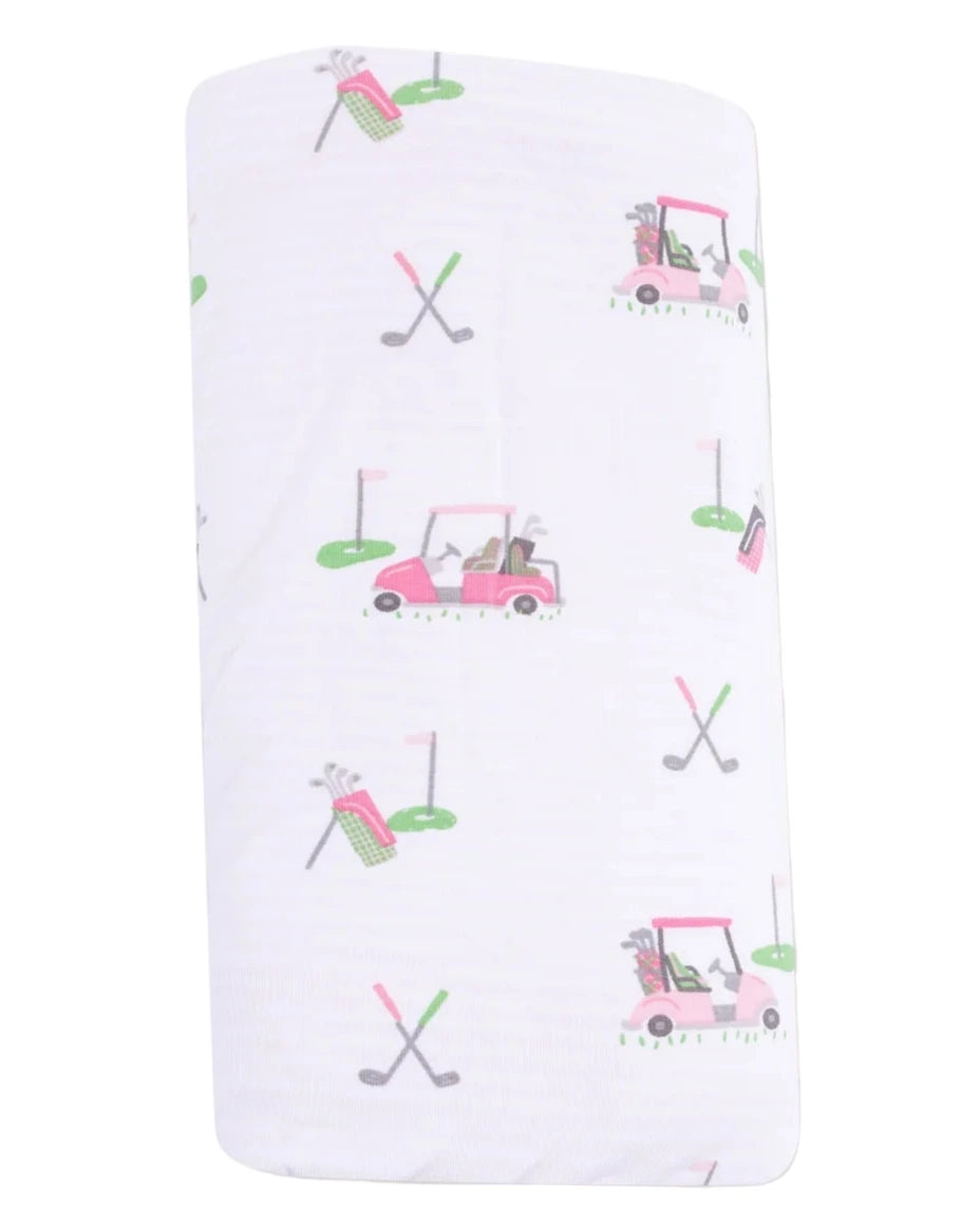 The Angel Dear Baby Golf Carts Ruffle Blanket features playful pink and green golf carts, clubs, flags, and bags on white fabric—perfect as a bamboo baby blanket or ruffle receiving blanket for little golf fans.