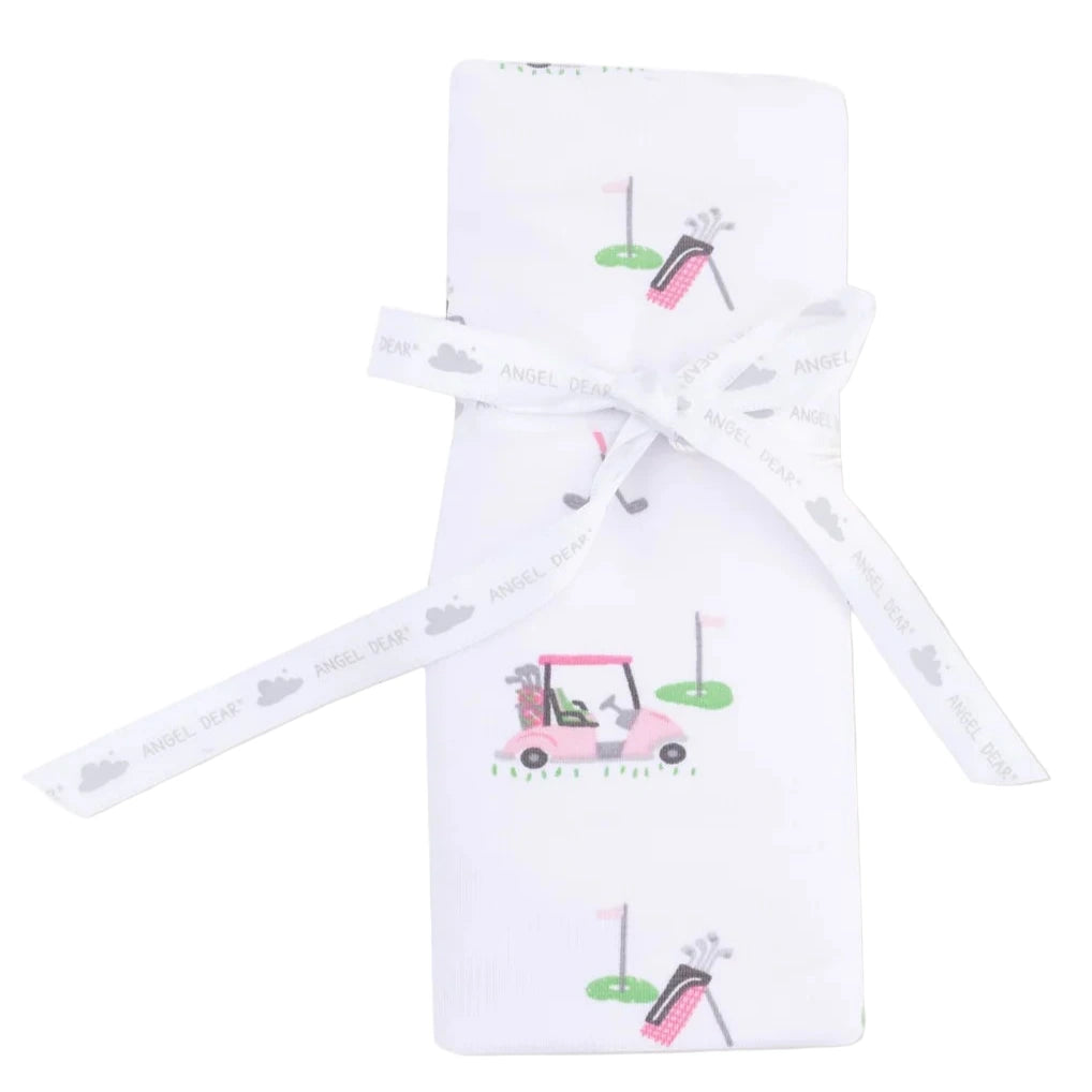 The Angel Dear Baby Golf Carts Ruffle Burp Cloth features a white fabric with golf cart and bag prints, folded and tied with a white ribbon displaying "ANGEL DEAR" and cloud motifs.