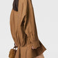 A person with long dark hair wears the Stella McCartney Washed Cotton Peplum Shirt Dress and carries a small brown quilted handbag.