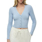 A woman wearing the Simkhai Ailany Cardigan, a light blue ribbed knit button-front cropped cardigan, paired with white drawstring pants.