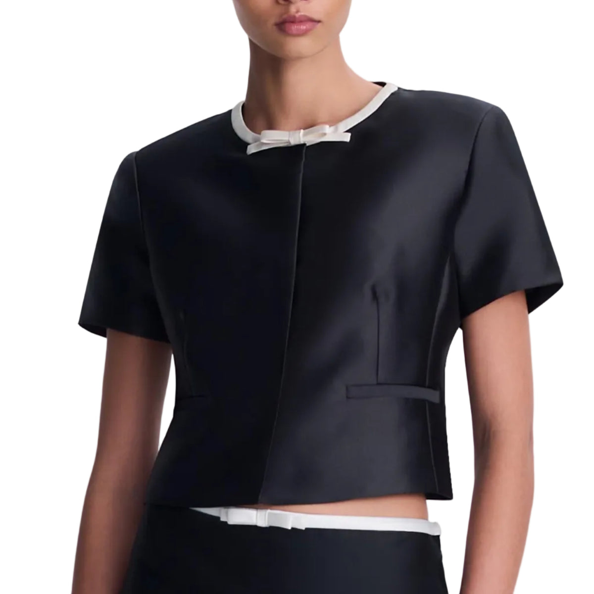 Simkhai Naelle top: a structured black short-sleeved shirt featuring a white round neckline with a bow detail and a matching bow at the waist.