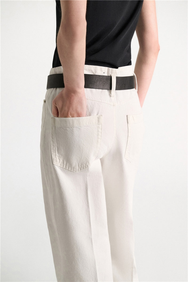 Off-white, wide-leg Dorothee Schumacher Denim Attraction Pant worn with a black belt and a hand in the back pocket.