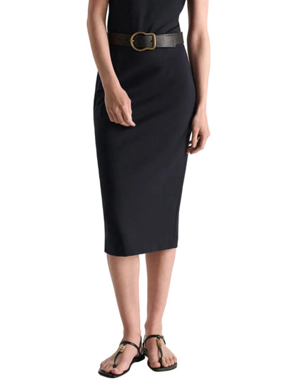 A person wearing the Dorothee Schumacher Emotional Essence Skirt with a black belt, black top, and black sandals stands against a white background—a true workweek essential.