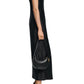 A woman in the Dorothee Schumacher Sense of Shine Dress, a stretch silk-satin midi with adjustable spaghetti straps, stands in profile wearing black strappy heels and holding a small black shoulder bag.