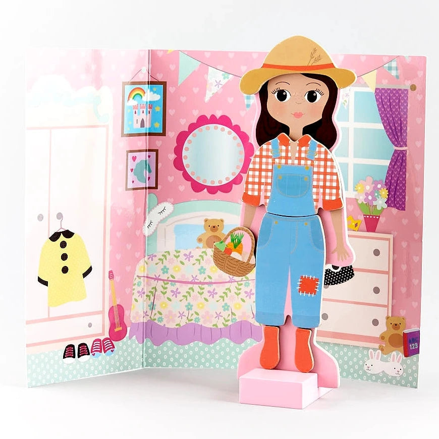 The Sophia Magnetic Dress Up Character by Floss and Rock features a paper doll dressed as a farmer standing in front of a fold-out bedroom backdrop with pink walls, toys, and decorations—perfect for creative role play and dress up adventures.
