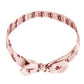 The Rylee & Cru Baby Bow Headband is a light pink fabric headband with a small floral pattern, knotted bow at the front, and soft scrunchy elastic band for comfort.