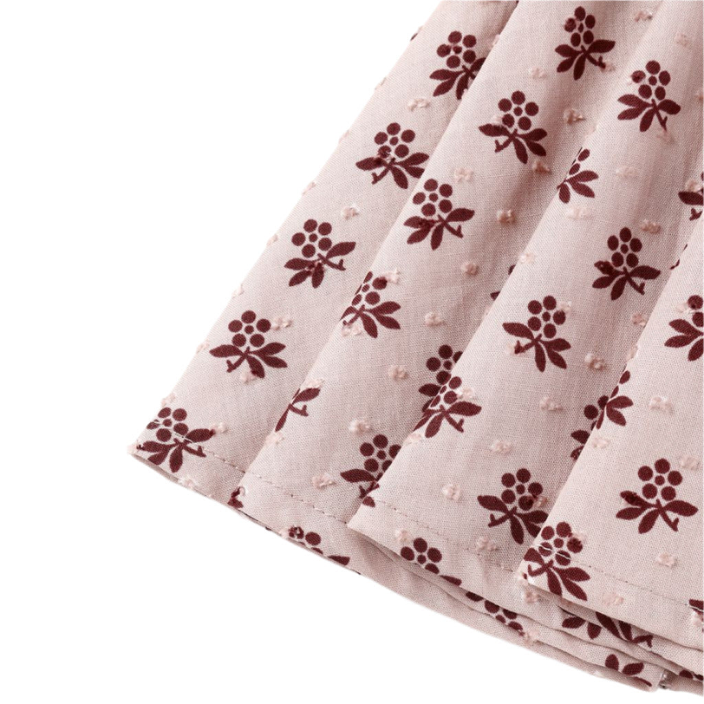 Close-up of the Rylee & Cru Baby Girls' and Girls' Rose Dress fabric, featuring pleats, a light pink background, maroon floral pattern, and textured dots—adding subtle Western charm.