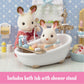 Two Calico Critters toy rabbits enjoy the Country Bathroom Set—a delightful miniature bathroom scene featuring realistic dollhouse furniture. One rabbit sits in the bathtub with included accessories, while the other stands beside holding a showerhead from the set’s bath tub with shower stand.