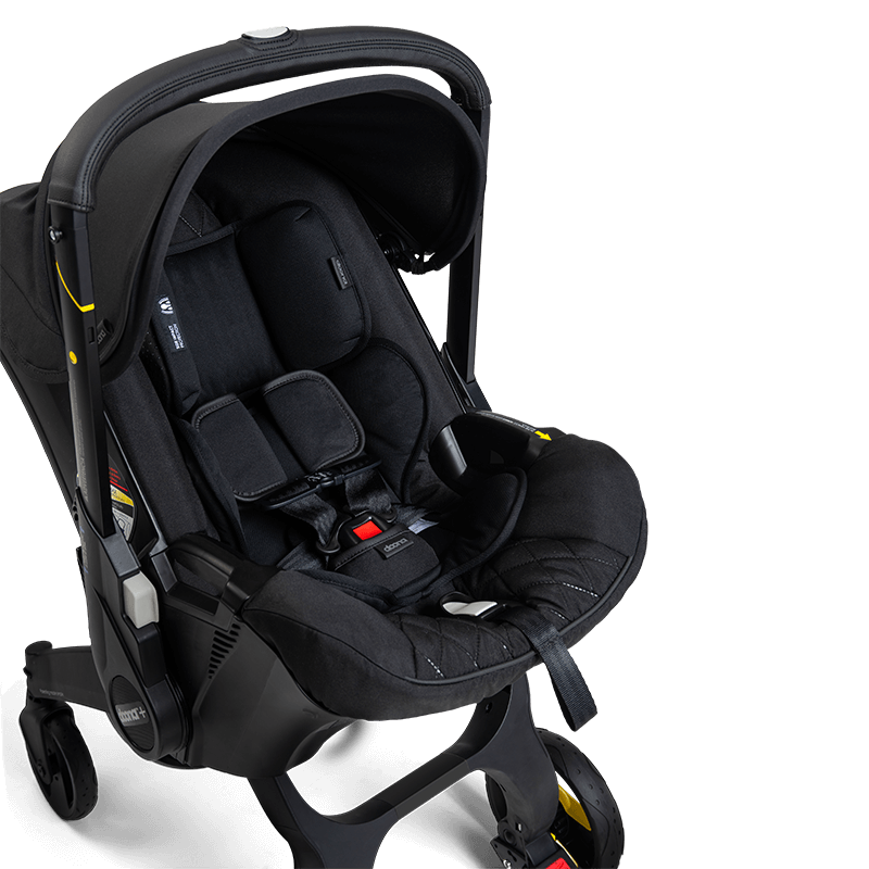 The Doona Car Seat and Stroller, Midnight Edition by Doona features a sleek black infant car seat with harness and padding, seamlessly attached to a four-wheel collapsible stroller frame. This travel system offers convenience and style in one integrated design.