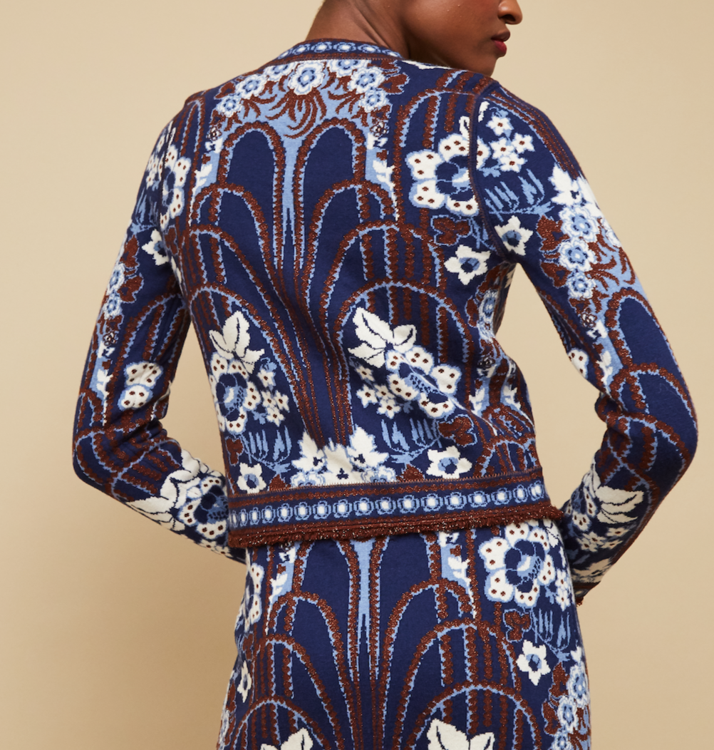 Person facing away from the camera wearing Cara Cara’s Livi Jacket, a blue, white, and brown floral jacquard knit.