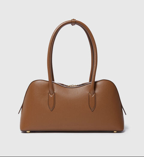 The Ryder Shoulder Bag by Stella McCartney, a brown vegan design with two handles, gold hardware, and a structured curved silhouette, is shown against a plain light gray background.