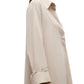 A woman wears TWP's Jenny's Crystal Gown, an oversized maxi shirt dress with cuffed long sleeves and a collar, shown in profile against a white background.