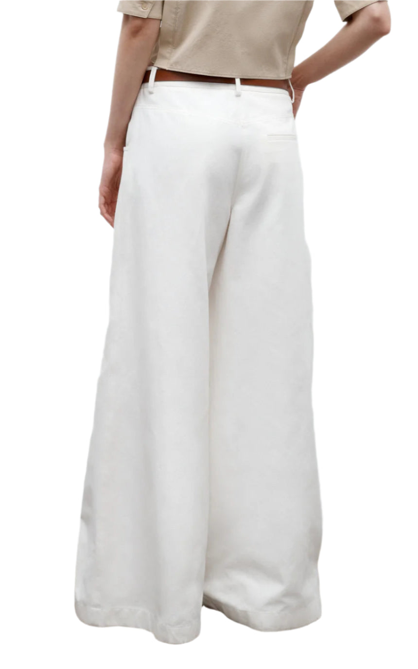 Model wearing TWP Dee's Linen Trouser—a relaxed fit, wide-leg white cotton linen style—paired with a beige cropped top, shown from the back against a plain white background.