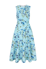 Introducing the Mara Magnolia Dress by Emilia Wickstead—a sleeveless, light blue A-line midi dress with a fitted bodice and flared skirt, beautifully decorated with a blue magnolia and green leaf print throughout.