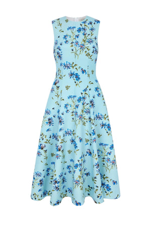 Introducing the Mara Magnolia Dress by Emilia Wickstead—a sleeveless, light blue A-line midi dress with a fitted bodice and flared skirt, beautifully decorated with a blue magnolia and green leaf print throughout.