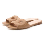 The Lido Sandal by Rupert Sanderson is a handmade tan open-toe slip-on, crafted in Italy from supple Cremino Calf leather with upper cutout detailing and flat wooden soles.
