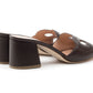 The Laguna Heel by Rupert Sanderson is a pair of black, open-back, block-heeled mules featuring decorative cutouts and tan insoles, expertly handmade in Italy.
