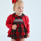 A toddler in The Beaufort Bonnet Company's Baby Girls' Dottie Hart Bubble, styled with a red cardigan and matching red bow, stands against a plain light background.