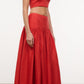 A woman wears the Staud Federico Linen Tank, a sleeveless red cropped top with adjustable straps, paired with a matching high-waisted, floor-length skirt, standing against a plain background.