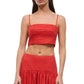 A woman models the Staud Federico Linen Tank, a sleeveless red top with spaghetti straps, paired with a matching high-waisted skirt, shown from mid-chest to mid-thigh.