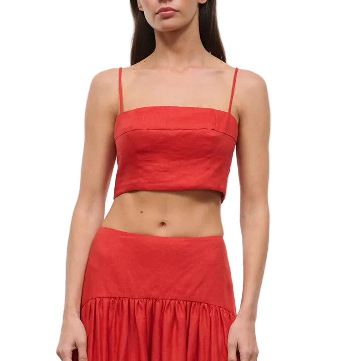 A woman models the Staud Federico Linen Tank, a sleeveless red top with spaghetti straps, paired with a matching high-waisted skirt, shown from mid-chest to mid-thigh.