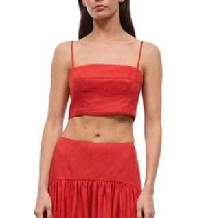 A woman models the Staud Federico Linen Tank, a sleeveless red top with spaghetti straps, paired with a matching high-waisted skirt, shown from mid-chest to mid-thigh.