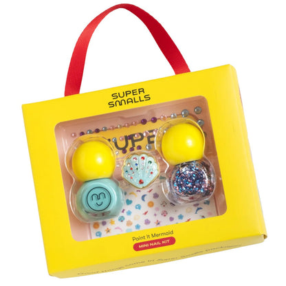 A yellow box labeled "Super Smalls Paint It Mermaid Mini Nail Kit" includes two peel-off nail polishes, a shell-shaped ring, and shell nail stickers, with a red carrying handle.