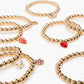 The Super Stack Bracelet Set by Super Smalls features gold beaded bracelets with heart, flower, and strawberry charms—an ideal mix-and-match accessory set for everyday wear, shown arranged on a white background.