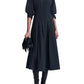 A black cotton poplin Jazz Embellished Collar Midi Dress by Simkhai with three-quarter sleeves, worn with black knee-high boots and a beaded fringe clutch.